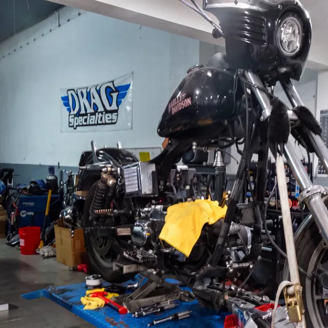 Harley-Davidson on the lift for repair, with a Road Glide in the background